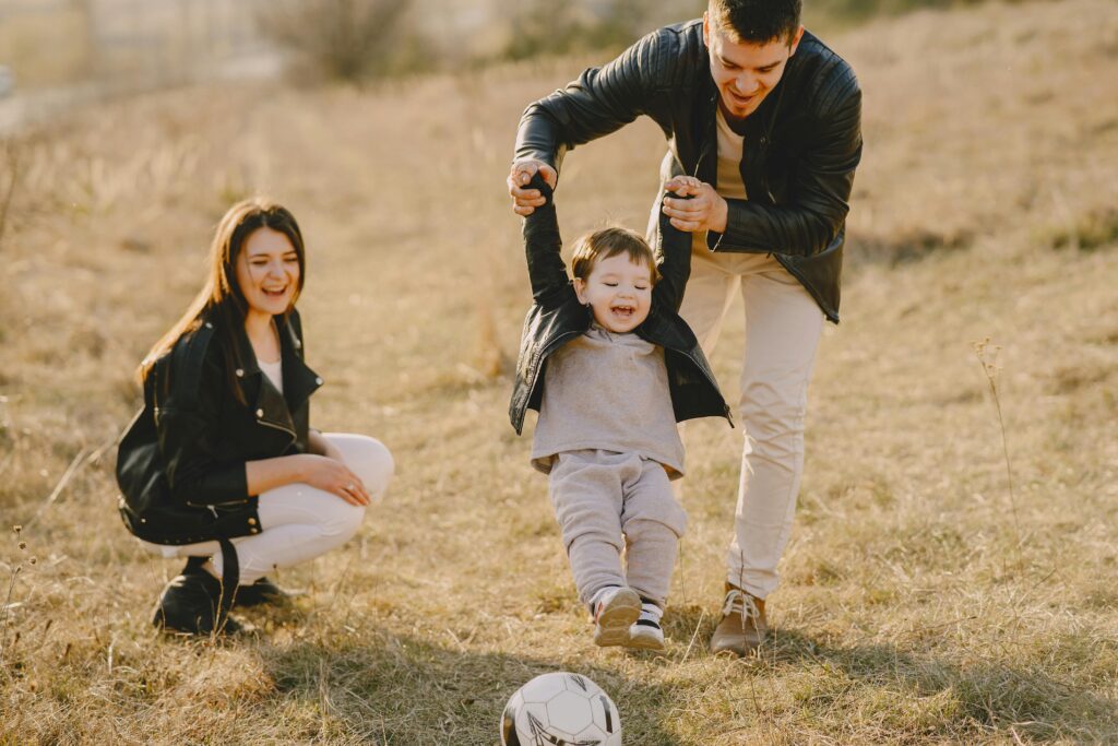 Family enjoying playful soccer game outdoors, capturing joyful moments.