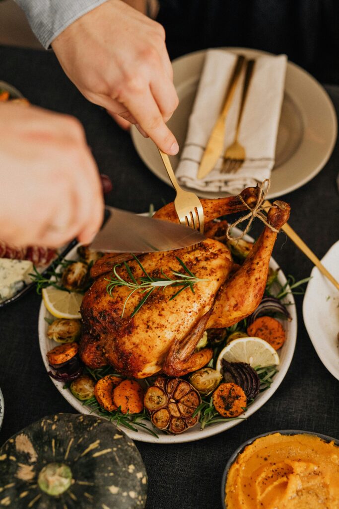 Close-up of a roast turkey being carved at a festive Thanksgiving dinner.