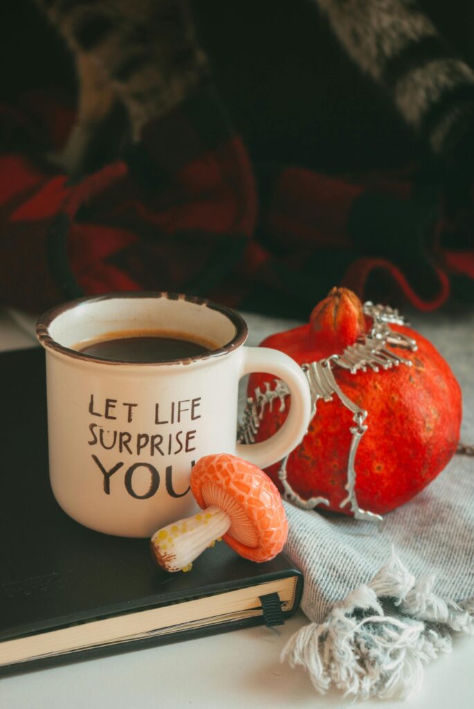 A warm autumn scene featuring a coffee mug, decorative pumpkin, and mushroom on a blanket.