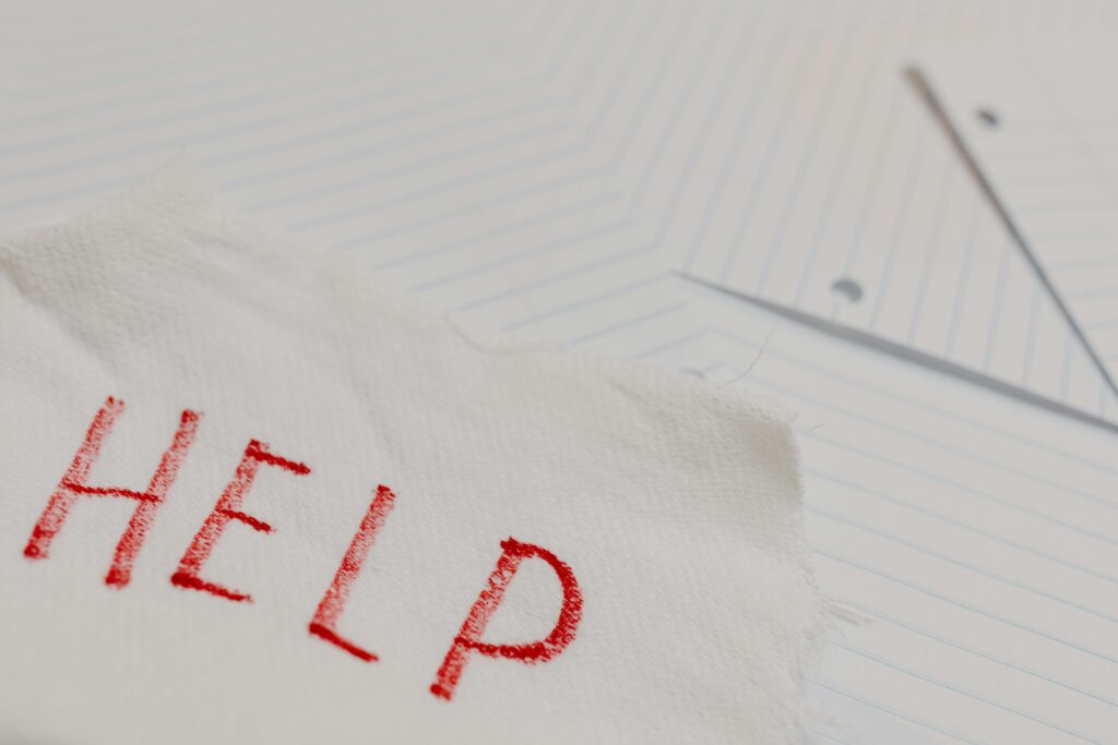 A raw and emotional depiction of a plea for help written on torn paper amidst lined sheets.